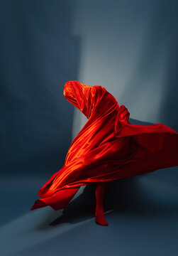 woman playing with red silk fabric on blu background