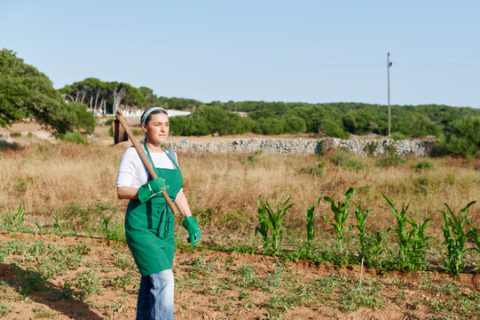 Woman walking with a hoe in her garden