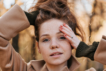 Portrait of a red-haired young girl in autumn outdoors.