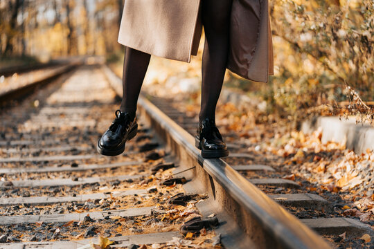 A girl walks in the autumn park on the tram tracks.