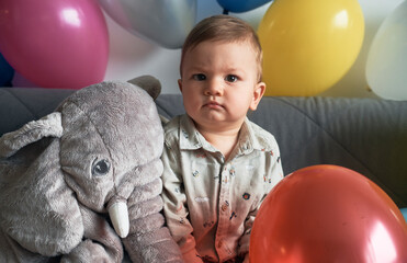 Baby boy with his elephant toy and lots of balloons