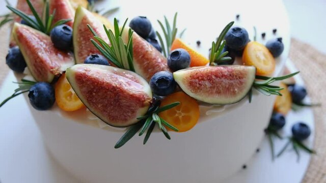 Close-up. Camera movement. Delicious homemade curd pie with a juicy filling, garnished with berries, figs and rosemary. Beautiful dessert presentation.