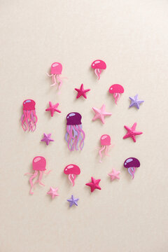 Many beautiful jellyfish and different starfish over beige background