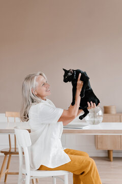 Cheerful mature woman holding cat