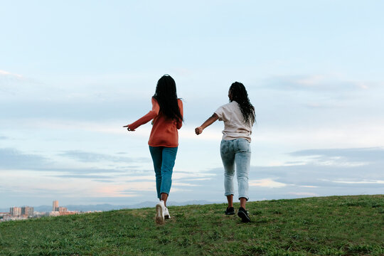 Back Of Two Young Women Running Away.