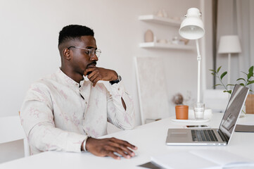 Serious young businessman using laptop at workplace