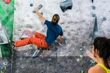 Elastic man climbing wall during workout with friends