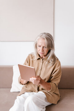 Puzzled elderly female using tablet