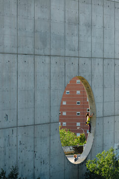 Athletic woman climbing round hole in wall