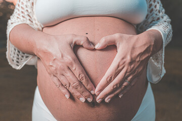pregnant woman making heart with hand on belly