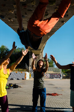 Happy friends supporting climber climbing wall