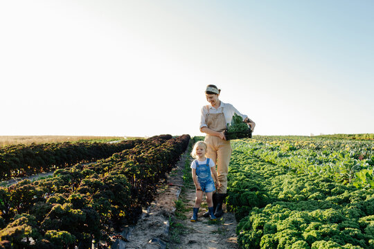 Female farmer with child harvesting greens in field