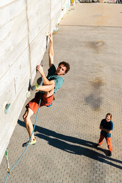 male climbing on bridge wall in park