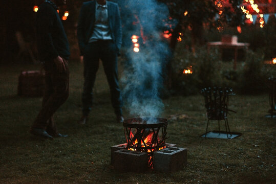 two men and a fire pit at dusk
