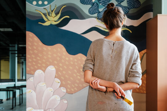 Anonymous artist admiring mural on wall