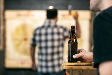 Focus On Beer With Friend Tossing Axe Behind
