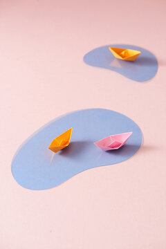 Paper ships of different colors on water background