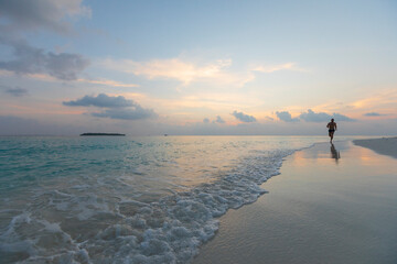 Man running barefeet on a Maldivian beach