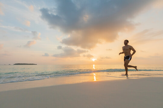 Man running barefeet on a Maldivian beach
