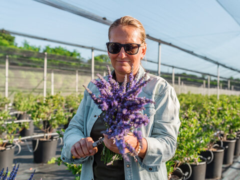 Positive florist making bouquet in hothouse