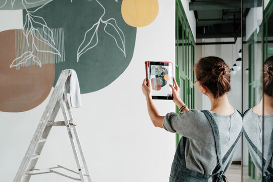 Unrecognizable woman taking picture of painted wall