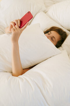 Girl under pillow with smart phone
