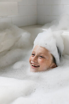 Happy Child Smiling while Taking a Bubble Bath with soap on head
