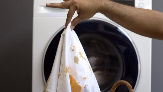 White cotton shirt So many stains and dirt. Stained ketchup The man's hand held the shirt and opened it to look at the dirt.
