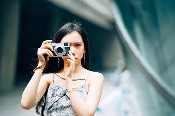 Portrait of young Asian woman using camera