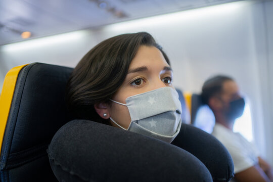 Woman With Medical Mask Flying On A Plane.