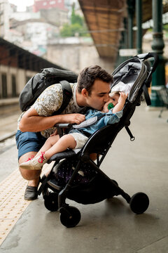 Father kissing baby in stroller on station