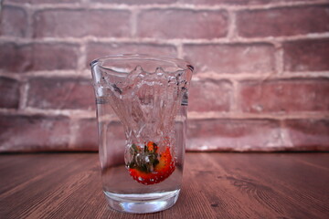 A strawberry that falls into the water with a splash effect
