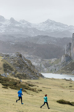 Man and woman running workingout on mountain trail in winter day