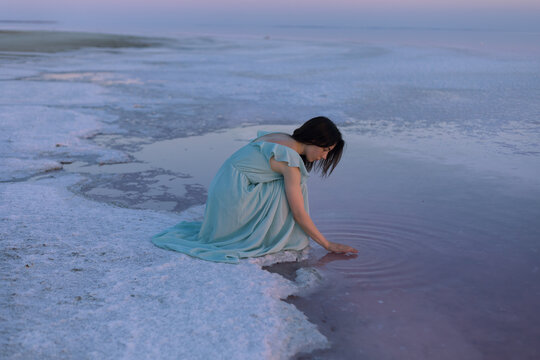 girl in a turquoise dress in the lake at sunset