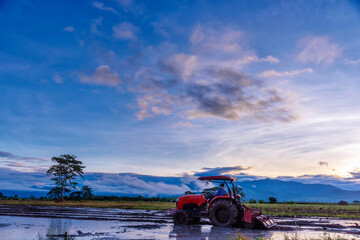 Farmers are plowing the fields using tractors in the morning