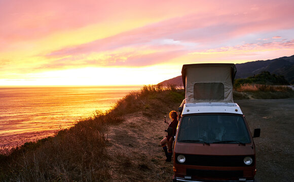 Wanderlust woman recording a beautiful sunset over the west coast of california during a roadtrip with her vintage campervan