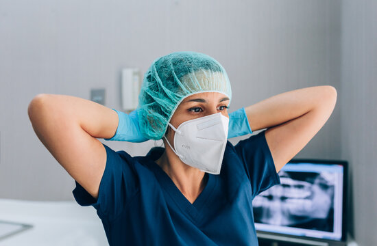 Dental surgeon woman wearing mask and cap while looking away wit