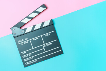 Fototapeta na wymiar The clapperboard on pink and blue background close-up, top view.