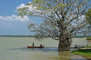 Fishermen in a dugout canoe lay their net along the shoreline of Tissa Lake in the shadow of a...