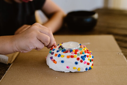 Kid making a candle holder with iron beads at home