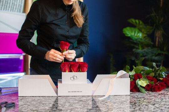 Female florist arranges nine red roses into a special surprise box package