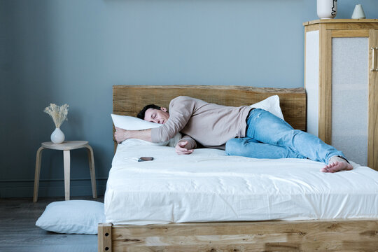 Tired man sleeping on bed in daylight