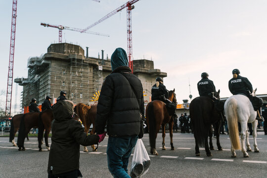 People Walking Behind A Formation Of Police Officers On Horses