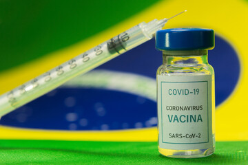 Vial of coronavirus Covid-19 vaccine with a syringe and a brazilian flag on the background. Brazil...