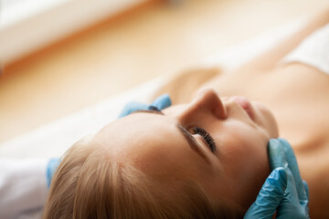 Obraz na płótnie Canvas Young pretty woman enjoying face massage procedure