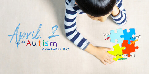 April 2 - World autism awareness day heading. A little Autistic boy staring and playing at colorful...