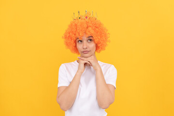 egoistic funny girl with fancy look wearing orange hair wig and princess crown, imagining