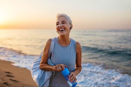 Happy female athlete with bottle of water near sea