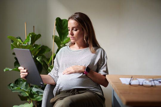 Pregnant employee using tablet near table
