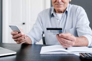 Senior man paying online with smartphone and credit card